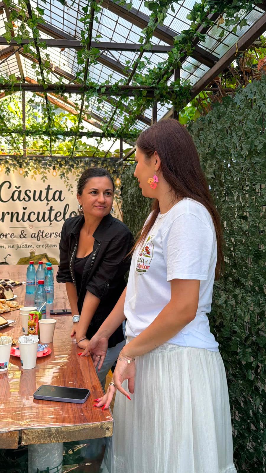 Două membre ale echipei Căsuței, sub pergolă