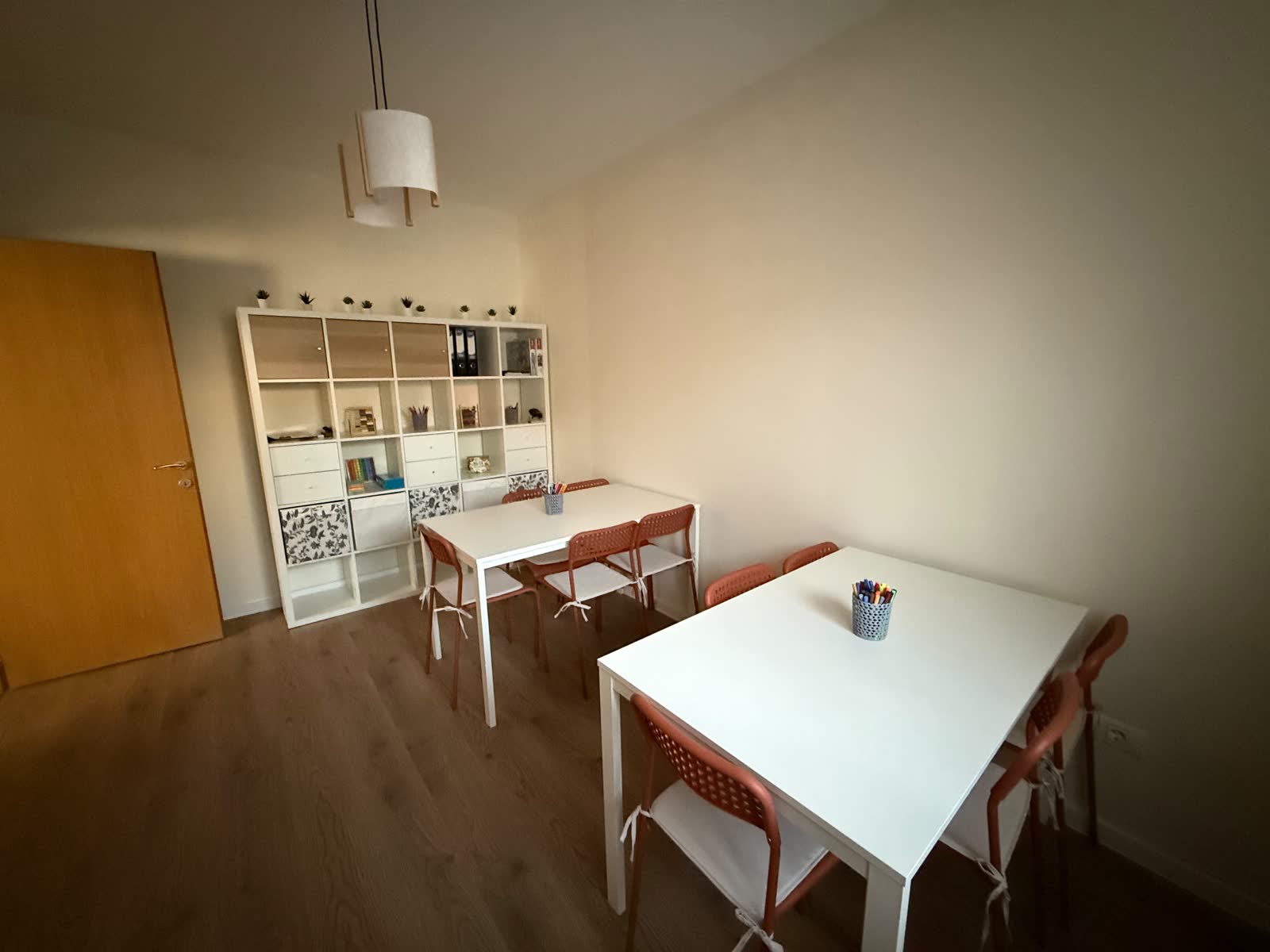 Sala mică văzută de la ușă, cu raftul alb de materiale